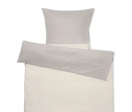 Linge de lit beige avec un oreiller gris sur le dessus.
