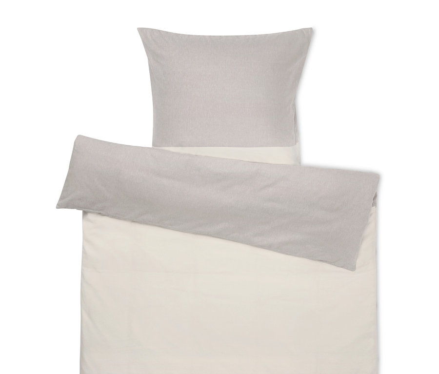 Linge de lit beige avec un oreiller gris sur le dessus.