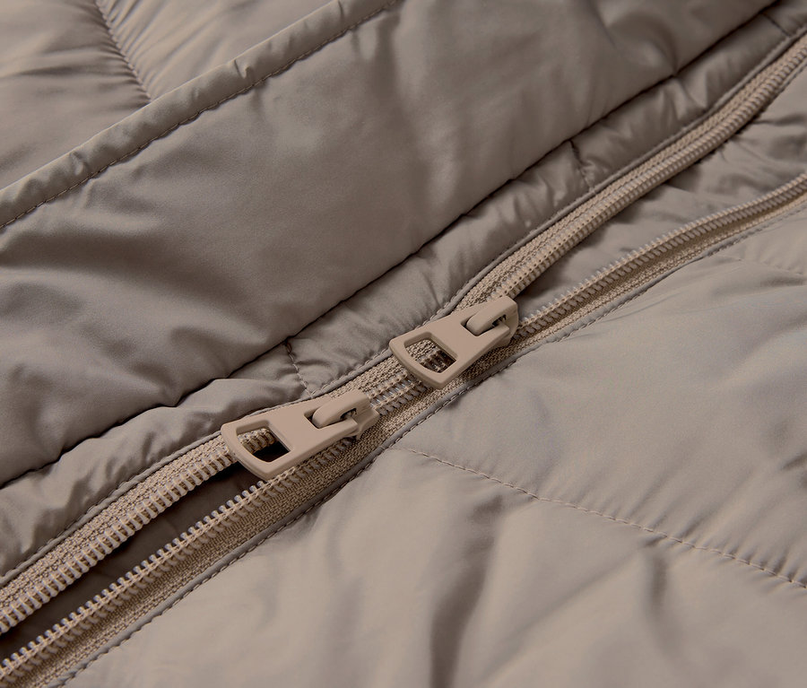 Gros plan sur une veste matelassée beige avec une fermeture éclair.