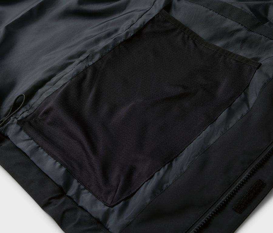 Gros plan sur une veste noire avec une poche zippée.