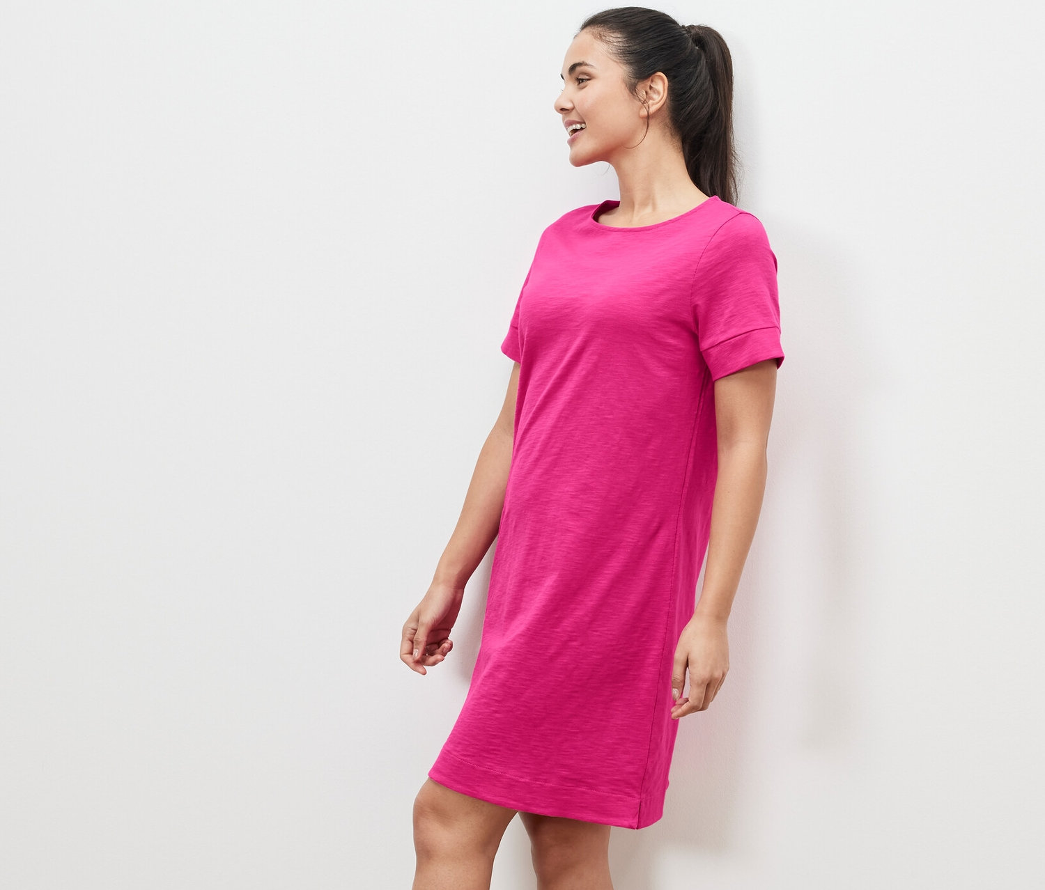 Femme debout de profil portant une robe en jersey rose.