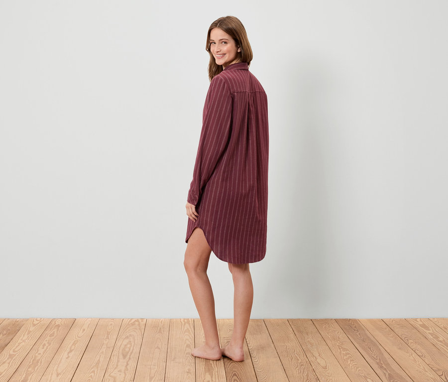 Une femme regarde par-dessus son épaule et pose dans une chemise de nuit rayée.