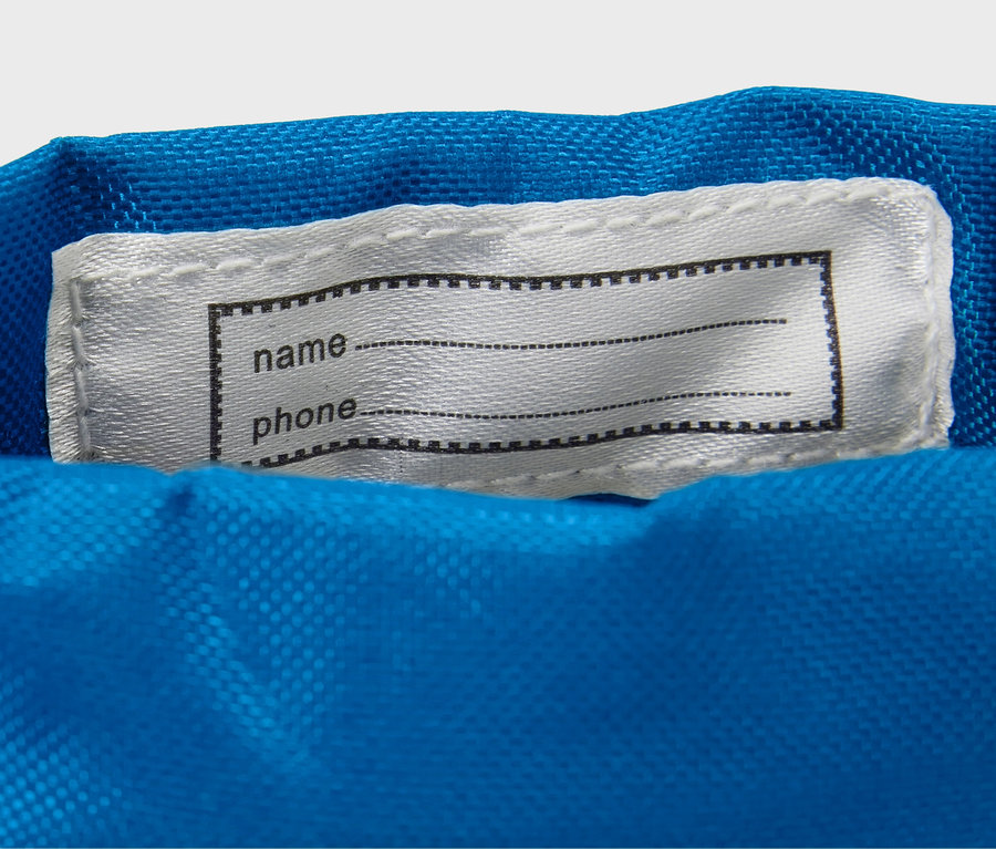 Sur un tissu bleu est cousue une étiquette blanche avec un cadre noir pour le nom et le téléphone.
