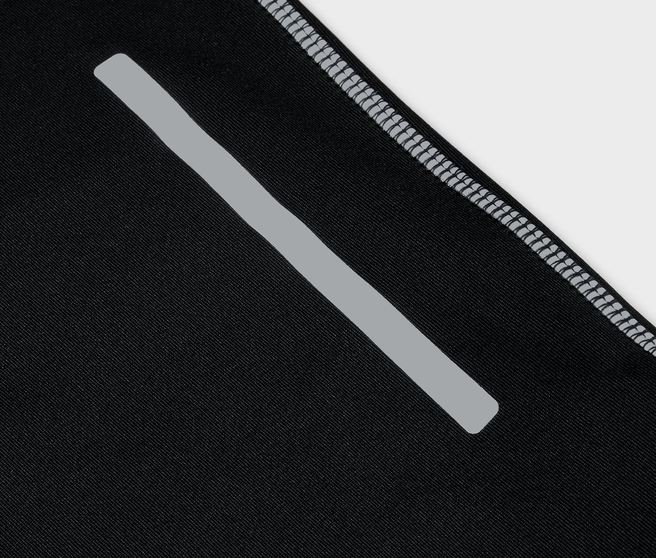 Gros plan d'un vêtement de sport noir avec une bande réfléchissante et un ourlet gris.