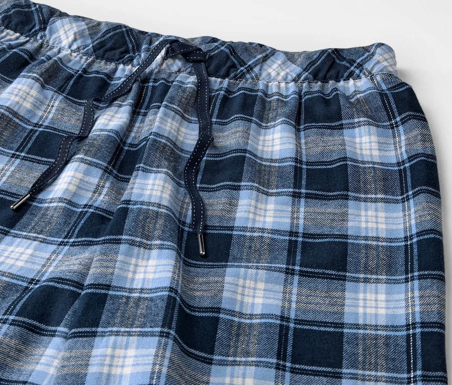 Gros plan d'un pantalon de pyjama en flanelle à carreaux bleus avec taille élastique et cordon de serrage.