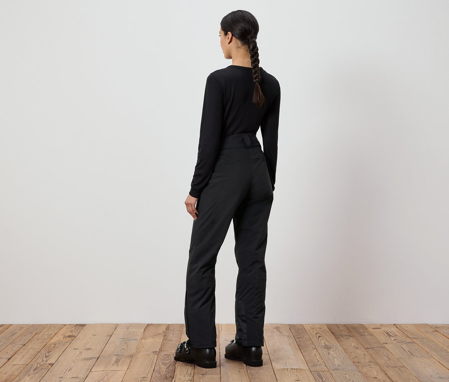 Une femme portant un pull et un pantalon noirs se tient dos à la caméra.