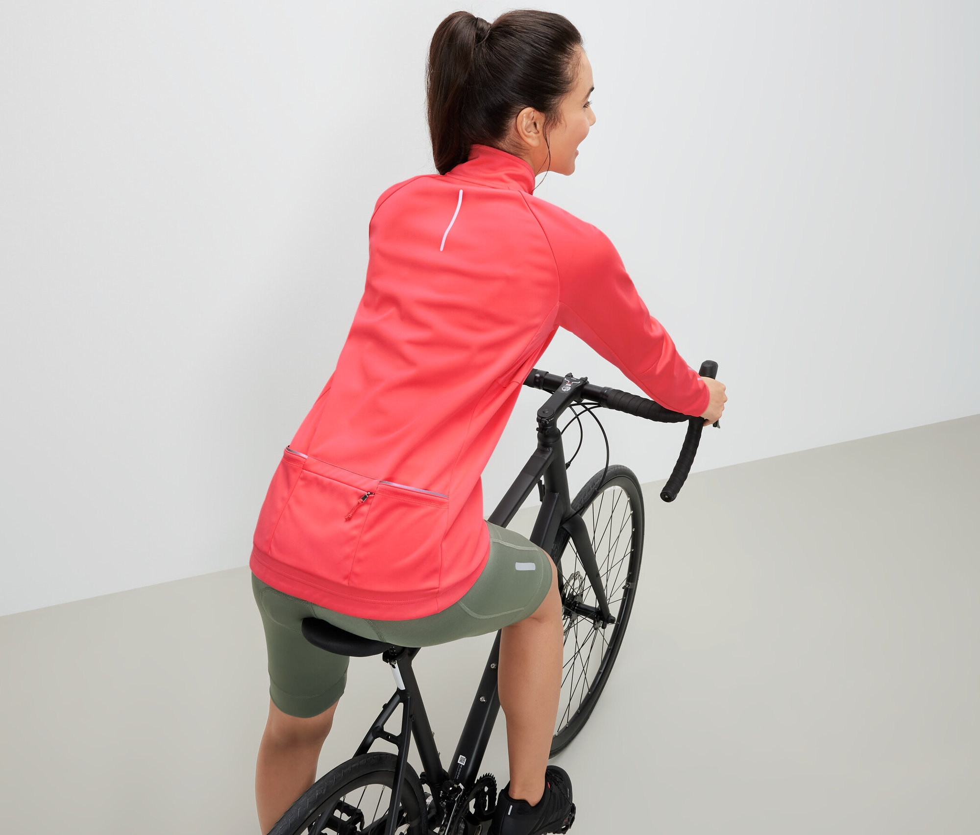 Femme sur un vélo portant une veste technique de cyclisme.