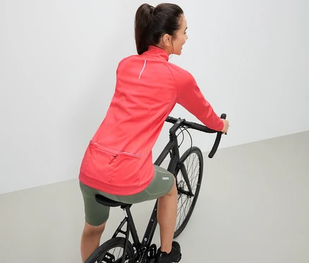 Femme sur un vélo portant une veste technique de cyclisme.