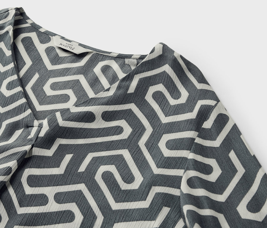 Gros plan d'une blouse aspect froissé avec un motif géométrique.