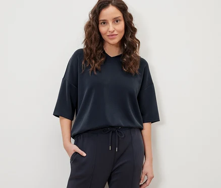 Femme posant en pull à capuche bleu foncé en mélange de modal et pantalon.
