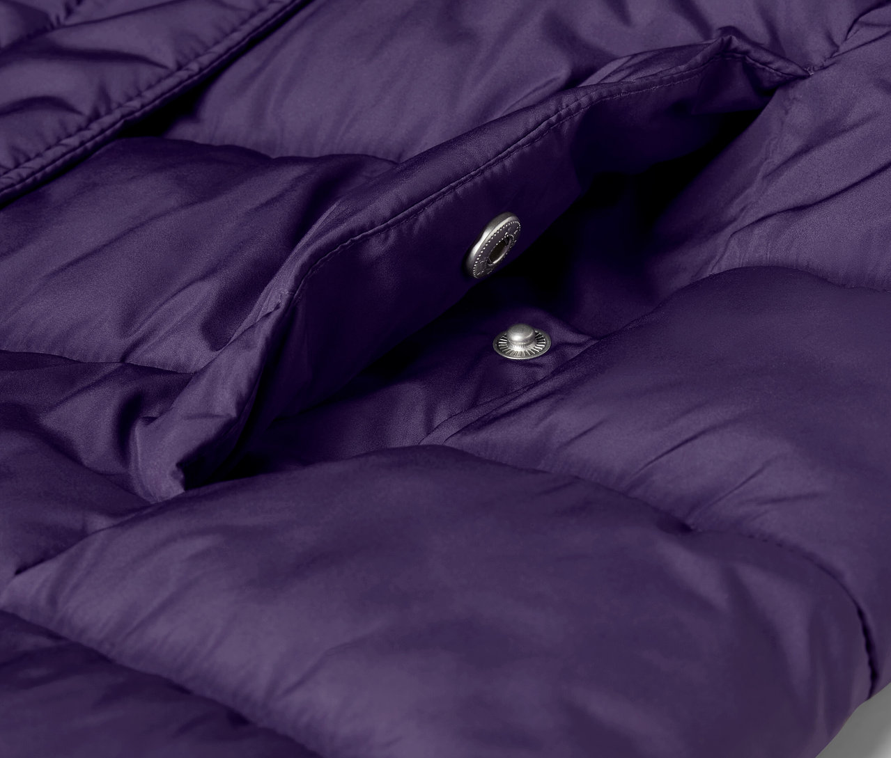 Gros plan sur une veste matelassée violette avec une poche et des boutons-pression argentés.