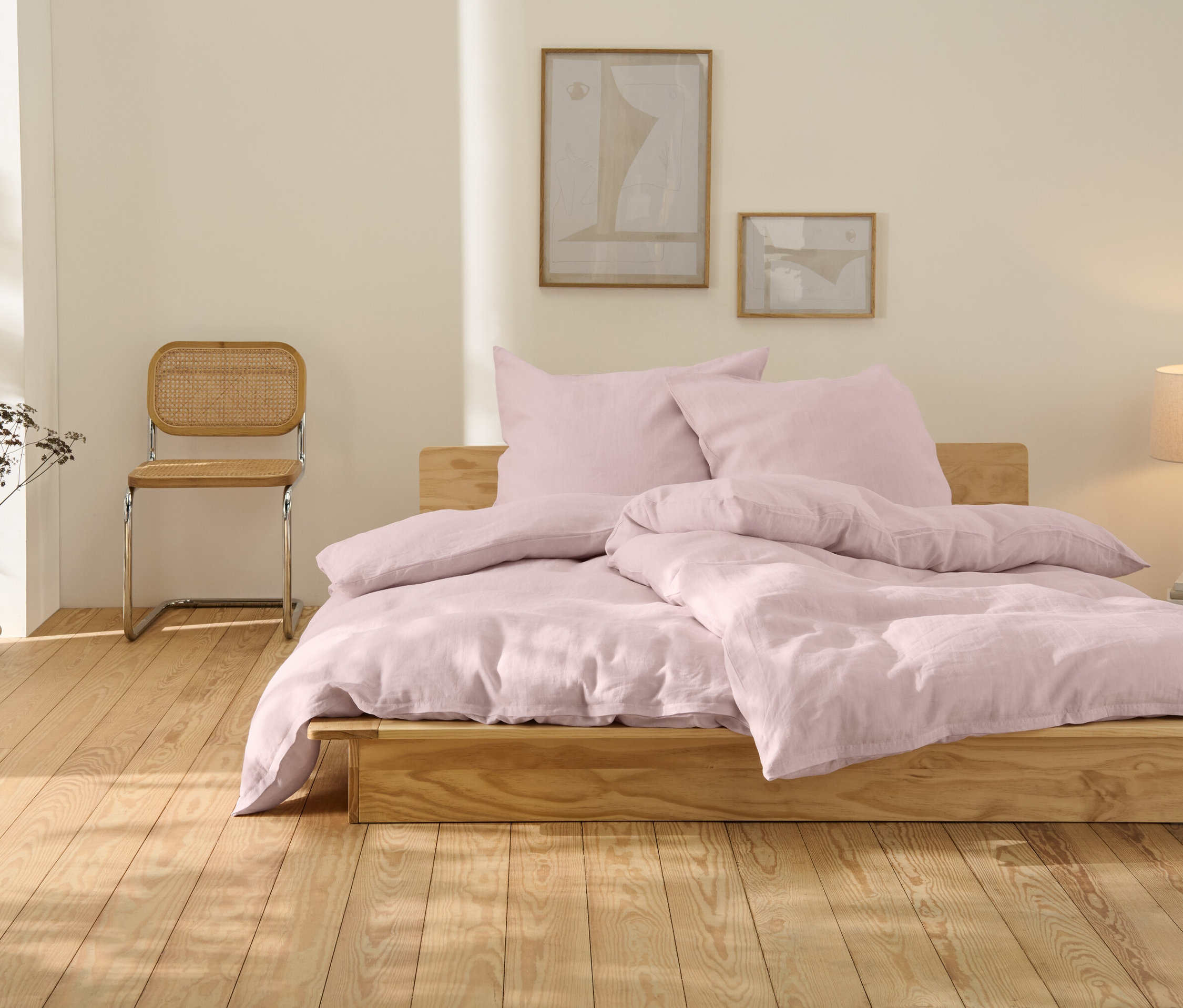 Une parure de lit en lin rose de grande taille est posée sur un lit en bois.