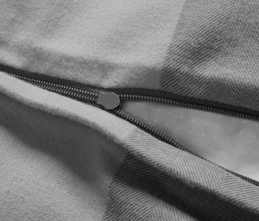 Gros plan d'une housse de couette grise avec fermeture éclair ouverte.