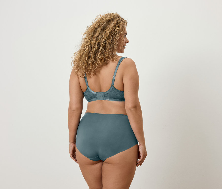 Vue arrière d'une femme aux cheveux ondulés portant un soutien-gorge et une culotte bleu sarcelle.