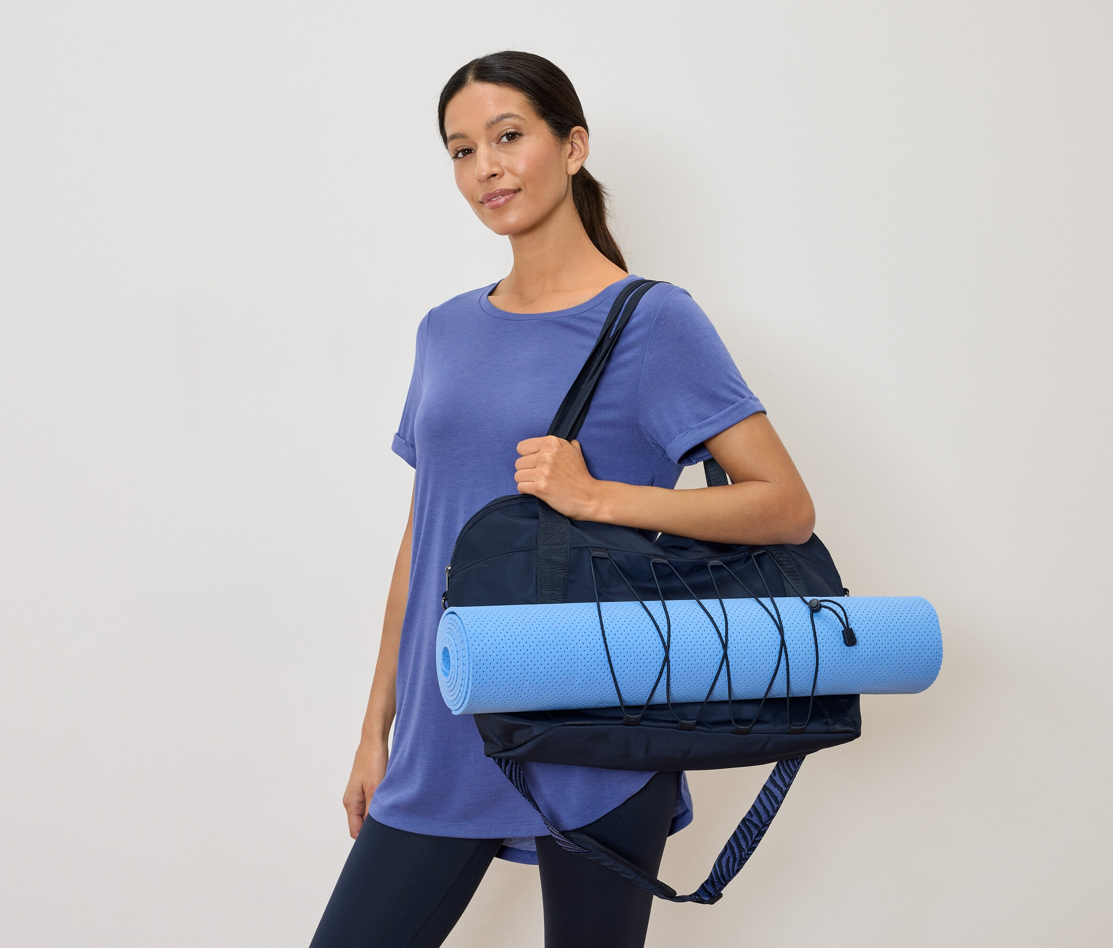 Femme avec un sac de sport bleu marine et un tapis de yoga bleu clair
