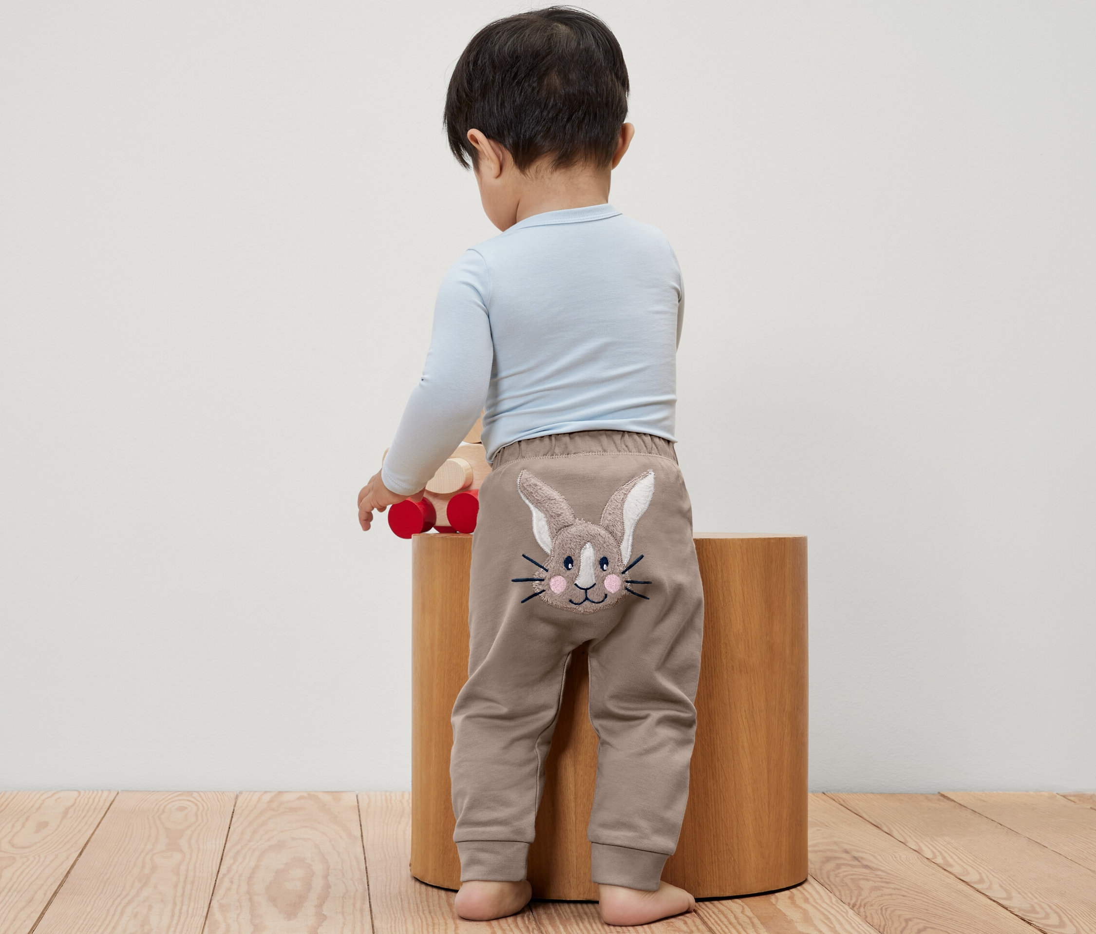 Un bébé est de dos et porte un pantalon pour bébé avec un motif de lapin.