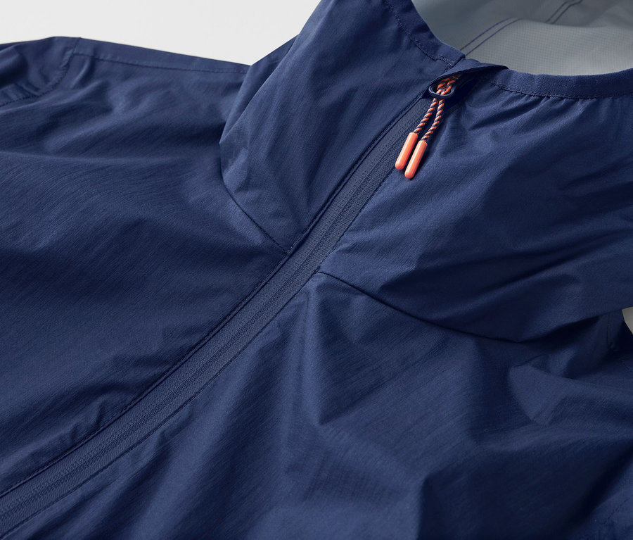 Gros plan sur une veste de pluie ultra-légère « repliable » avec capuche et fermeture éclair.