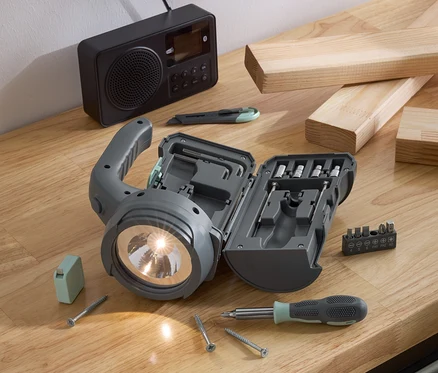 Lampe multifonction LED 17-en-1 avec accessoires sur une table en bois.