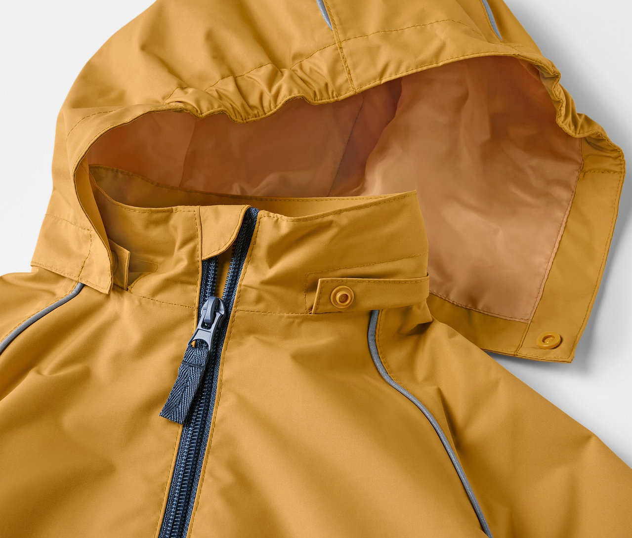 Gros plan sur une veste de pluie pour enfant ocre avec capuche et fermeture éclair.