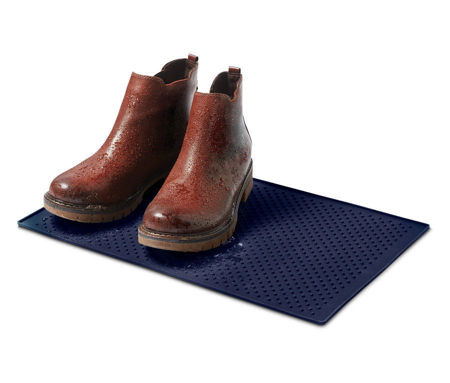 Deux bottines en cuir marron sont posées sur un tapis bleu avec des gouttes d'eau.