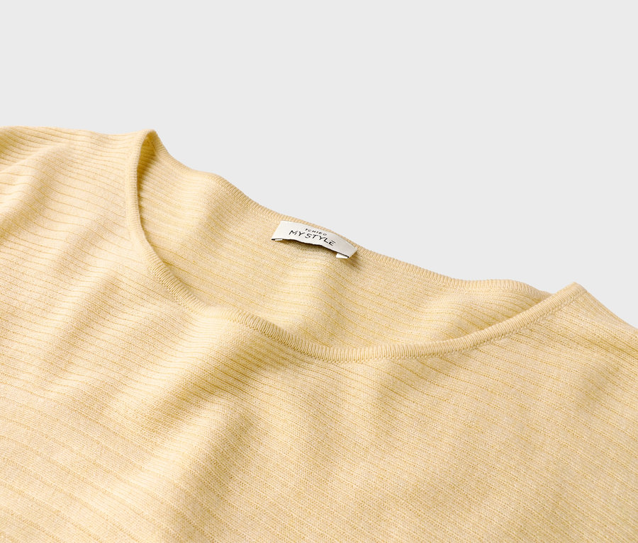 Gros plan d'un pull côtelé jaune clair avec une étiquette indiquant « ICHIGO MYSTYLE ».