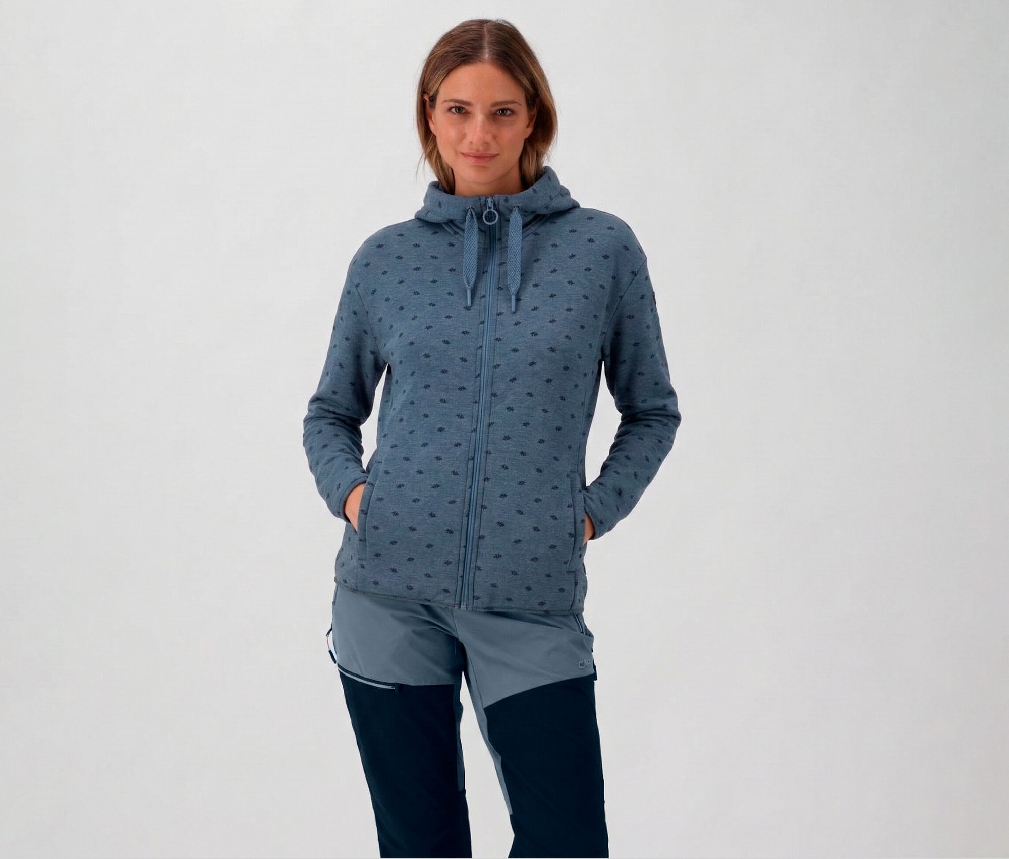 Femme portant un sweat à capuche et une veste polaire CMP pour femme avec capuche bleue, les mains dans les poches.