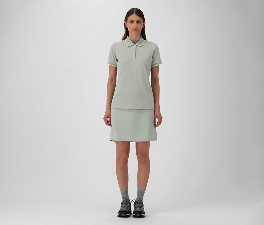 Femme portant une jupe d’extérieur CMP et un polo pour femme CMP en piqué stretch pistache, avec des chaussettes grises et des chaussures de randonnée.