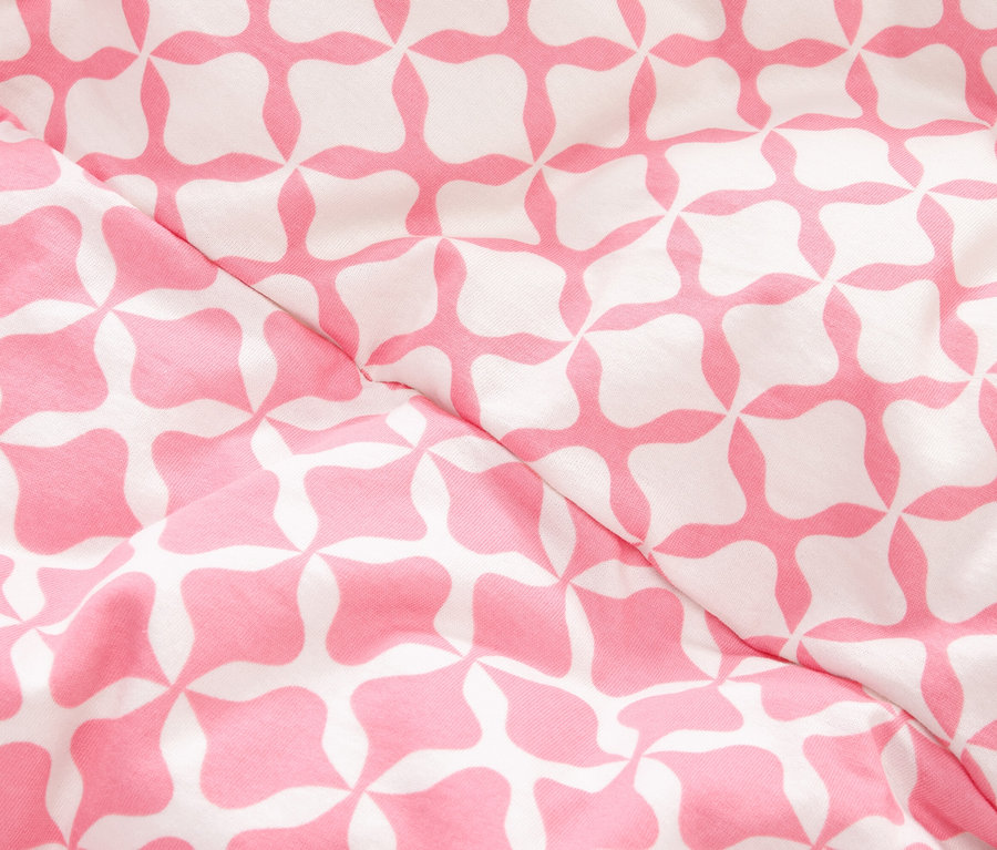Gros plan d'un tissu à motif géométrique rose et blanc.