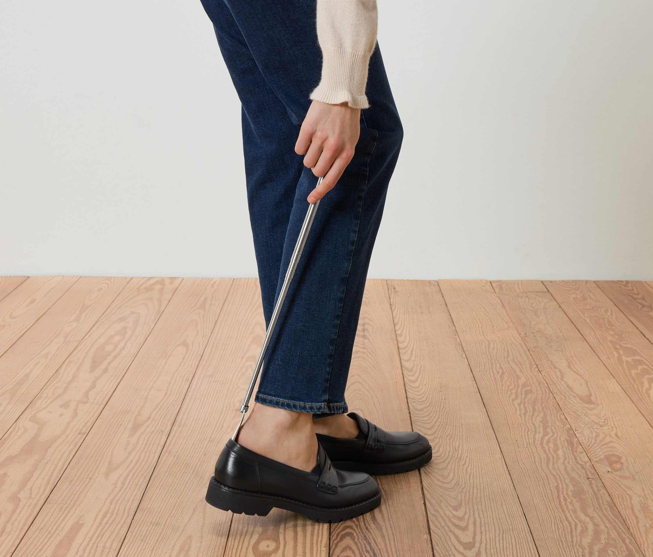 Personne mettant des mocassins noirs avec un chausse-pied.