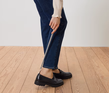 Personne mettant des mocassins noirs avec un chausse-pied.