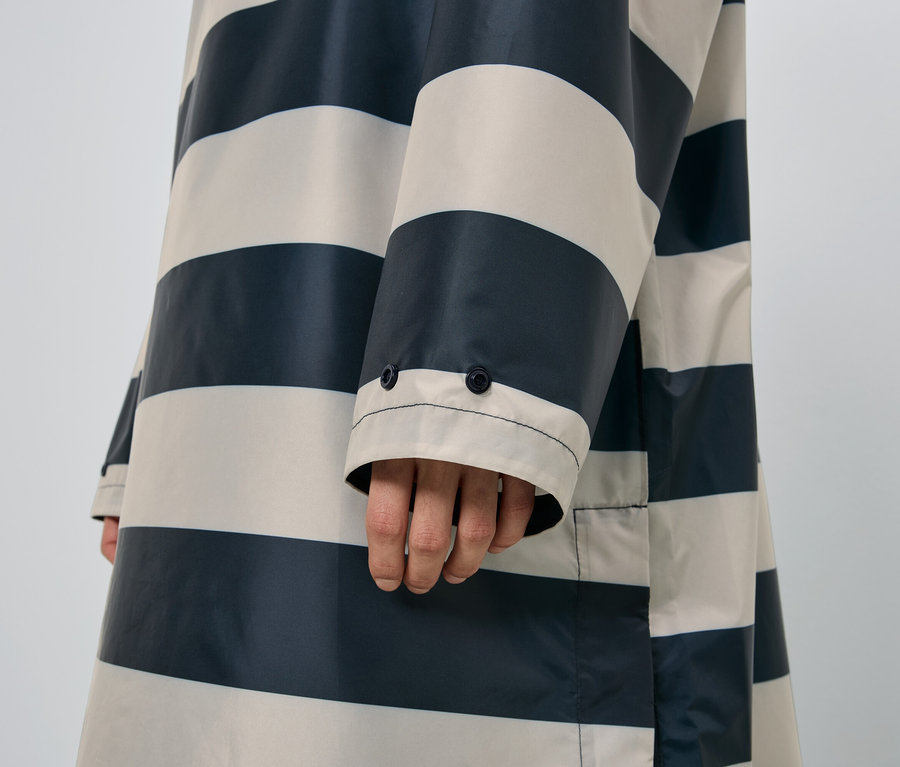 Gros plan sur un bras portant un imperméable rayé.