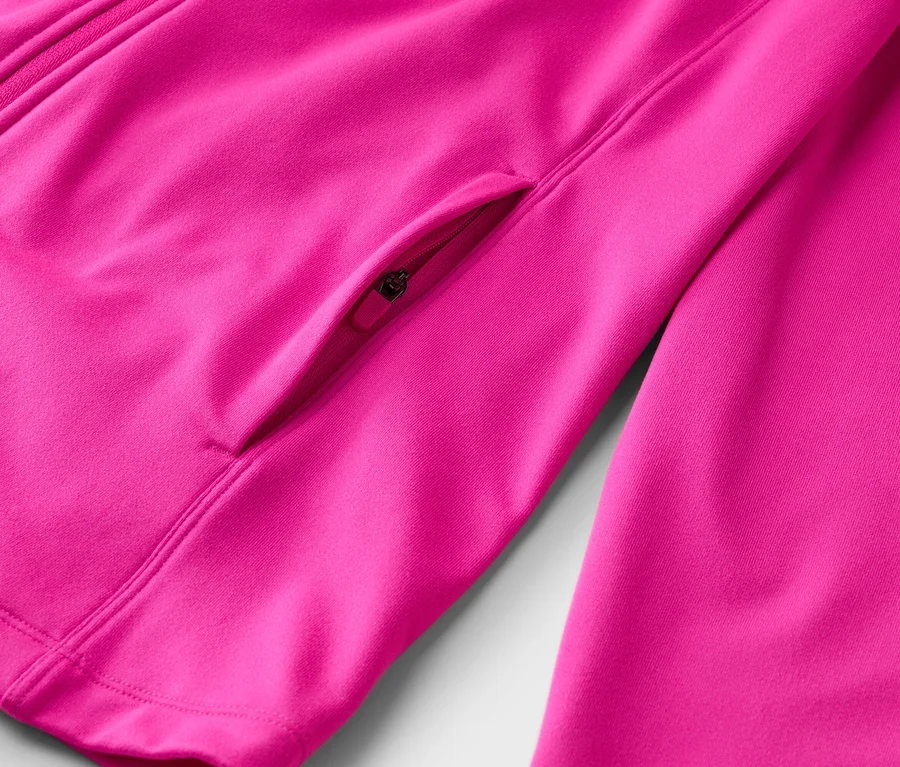 Gros plan d'une veste rose avec une fermeture éclair et une petite poche zippée.