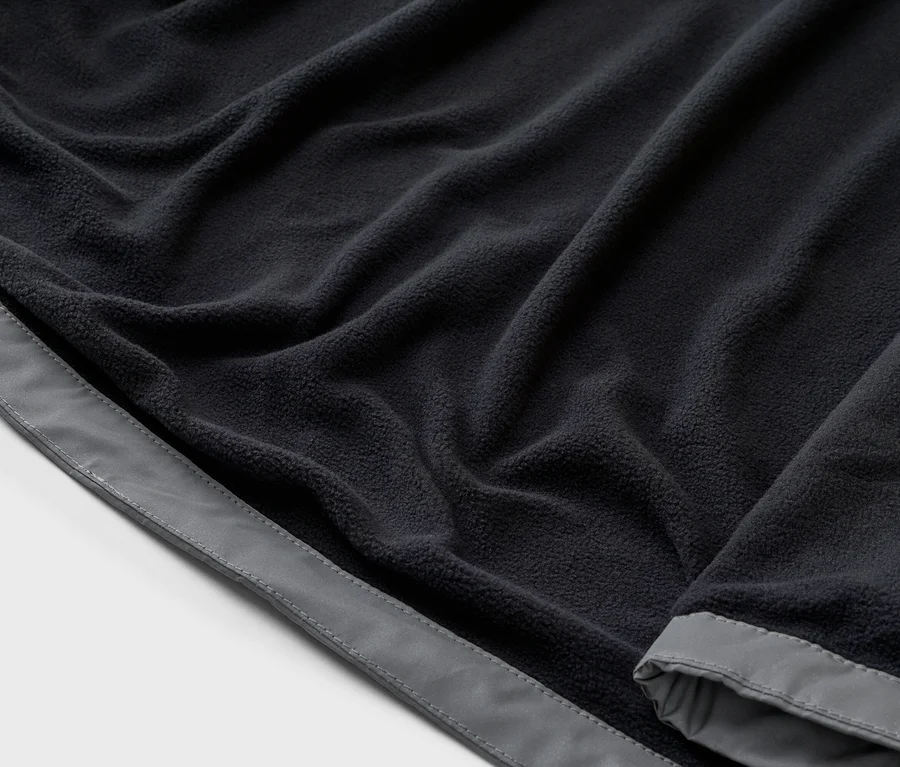 Gros plan d'un tissu polaire bleu marine avec une bordure grise, disposé en plis.