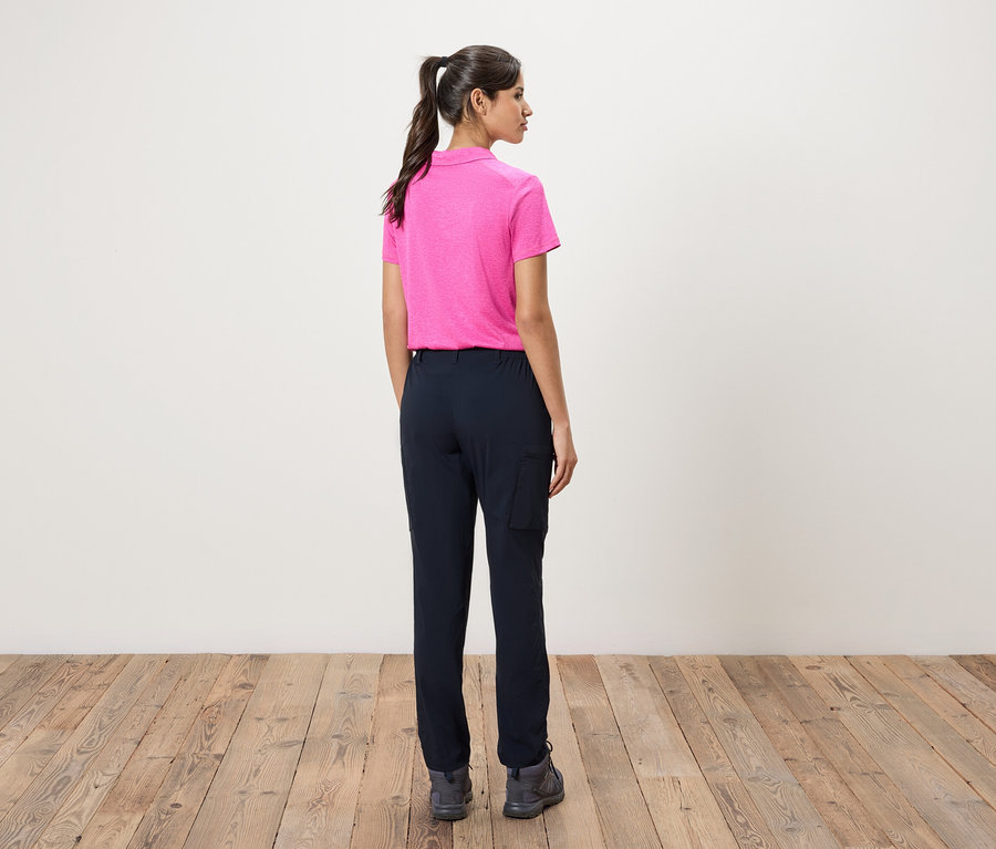 Femme debout, dos à la caméra, portant un polo rose et un pantalon cargo bleu marine.