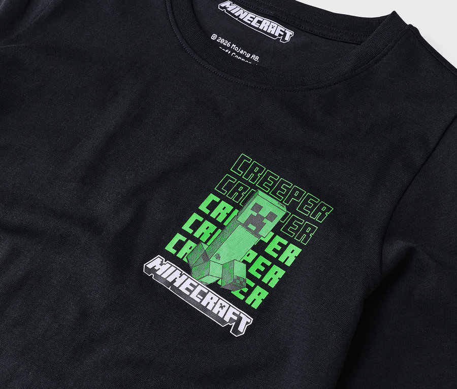 Gros plan d'un t-shirt noir à manches longues avec un motif Minecraft Creeper vert.
