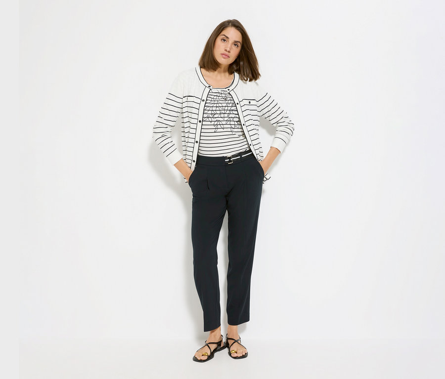 Femme portant un t-shirt Olsen sous un cardigan Olsen «
LA
» rayé, avec un pantalon foncé et des sandales.