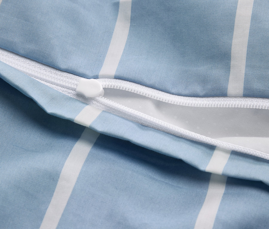 Gros plan d'une housse de couette partiellement ouverte avec un motif à rayures bleues et blanches et une fermeture éclair blanche.