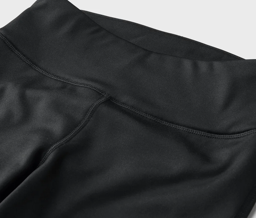 Gros plan sur des leggings noirs taille haute avec des coutures apparentes.