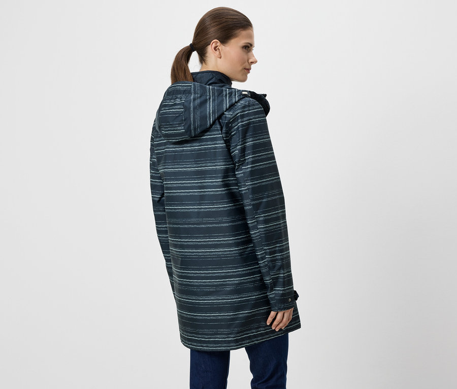 Femme vue de dos portant un imperméable bleu rayé à capuche et un jean sur fond blanc.