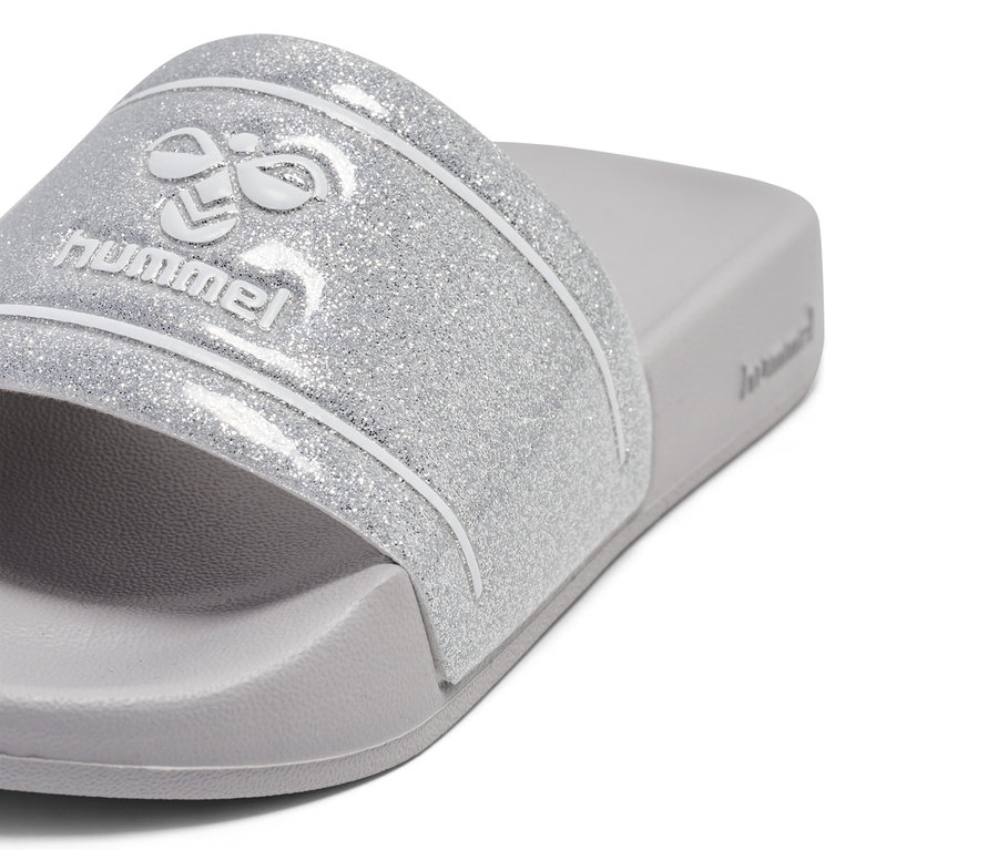 Gros plan sur des tongs de bain hummel® Pool Slide GlitterJR argentées à paillettes avec logo sur une semelle intérieure grise.
