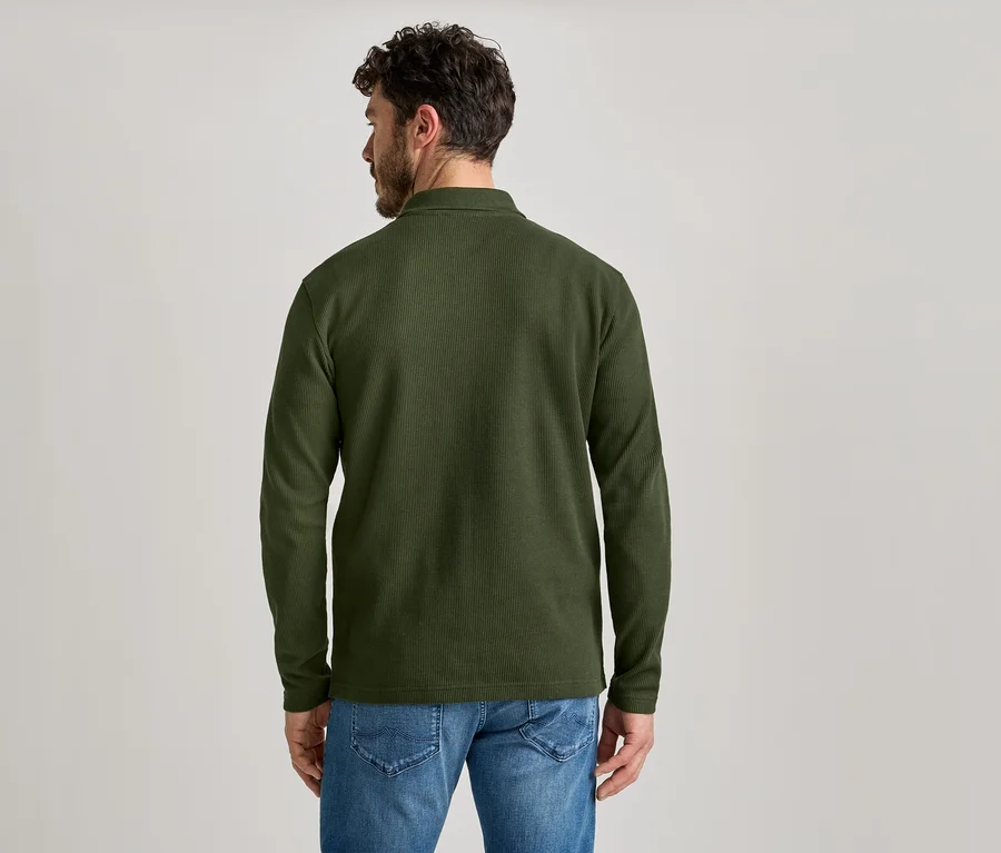 Vue arrière d'un homme barbu portant une chemise en velours côtelé vert olive et un jean.