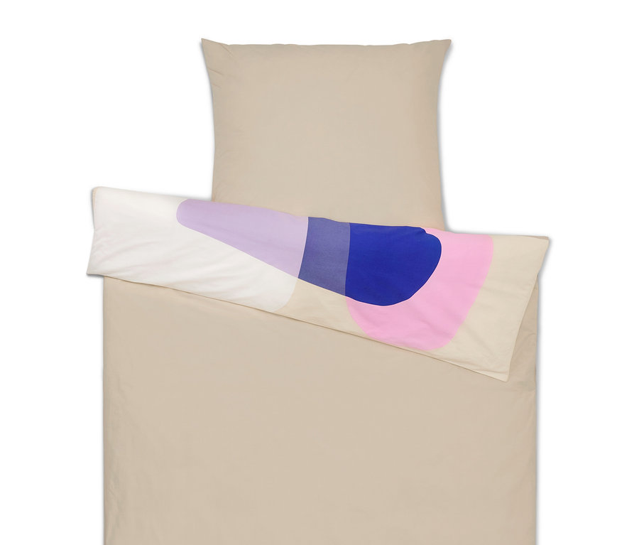 Linge de lit beige avec oreiller et coussin aux formes abstraites violettes, bleues et roses.