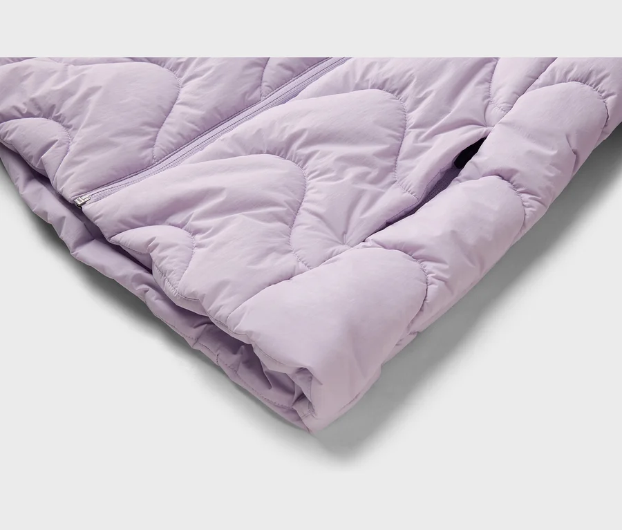 Gros plan d'une veste matelassée violet clair avec une fermeture éclair et une poche latérale.