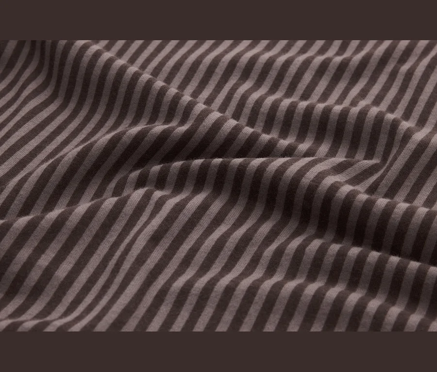 Tissu drapé avec des rayures alternées marron foncé et marron clair, montrant des plis doux.