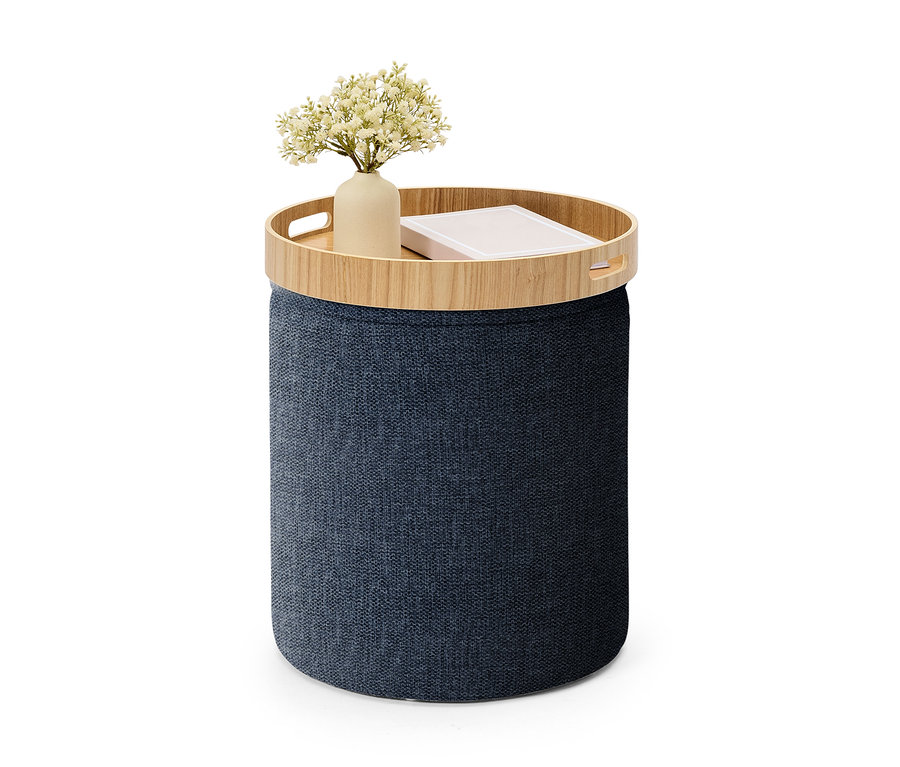 Pouf de rangement cylindrique bleu foncé avec un plateau en bois, sur lequel se trouvent un vase de fleurs blanches et un livre.