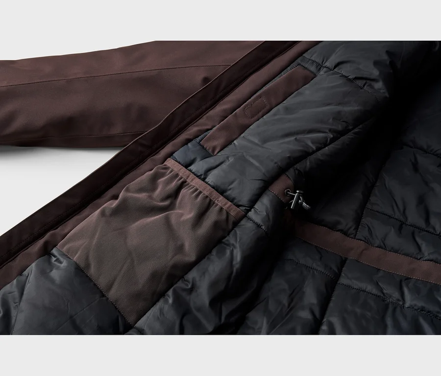 Gros plan de l'intérieur d'une veste marron, montrant sa doublure matelassée noire, une poche intérieure en tissu marron et un stoppeur de cordon.