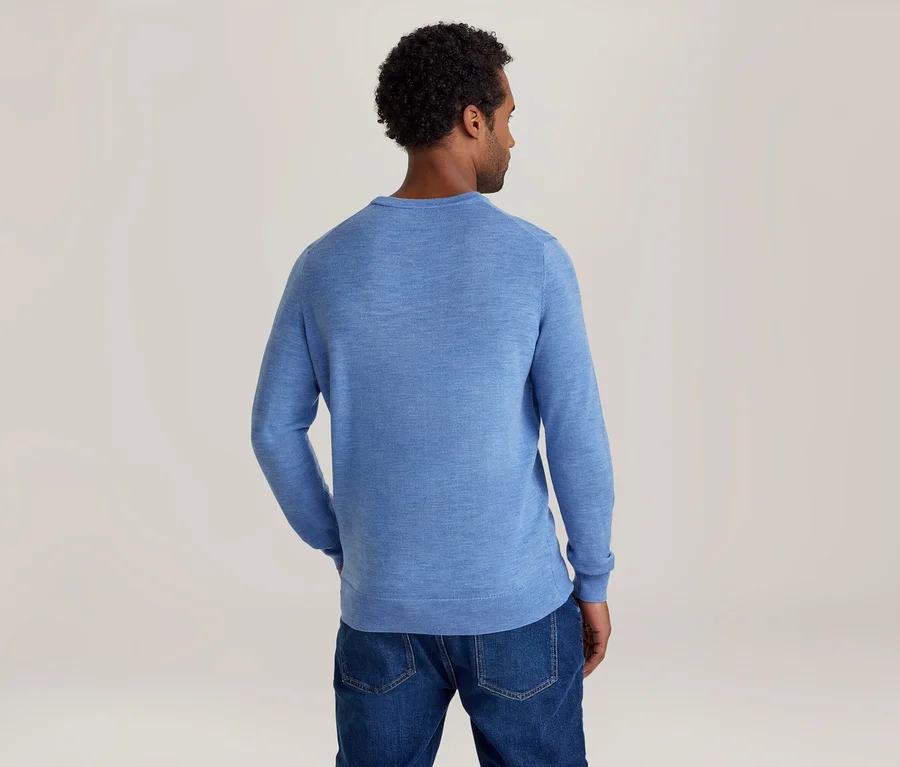 Homme vu de dos, portant un pull à manches longues bleu clair et un jean bleu.