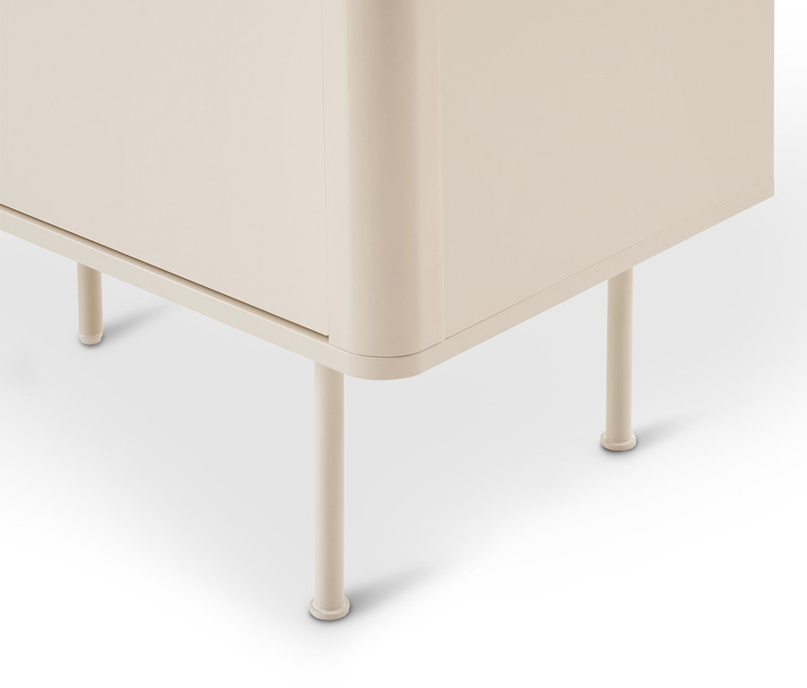 Coin inférieur d'une armoire beige clair aux bords arrondis, reposant sur quatre pieds cylindriques fins.