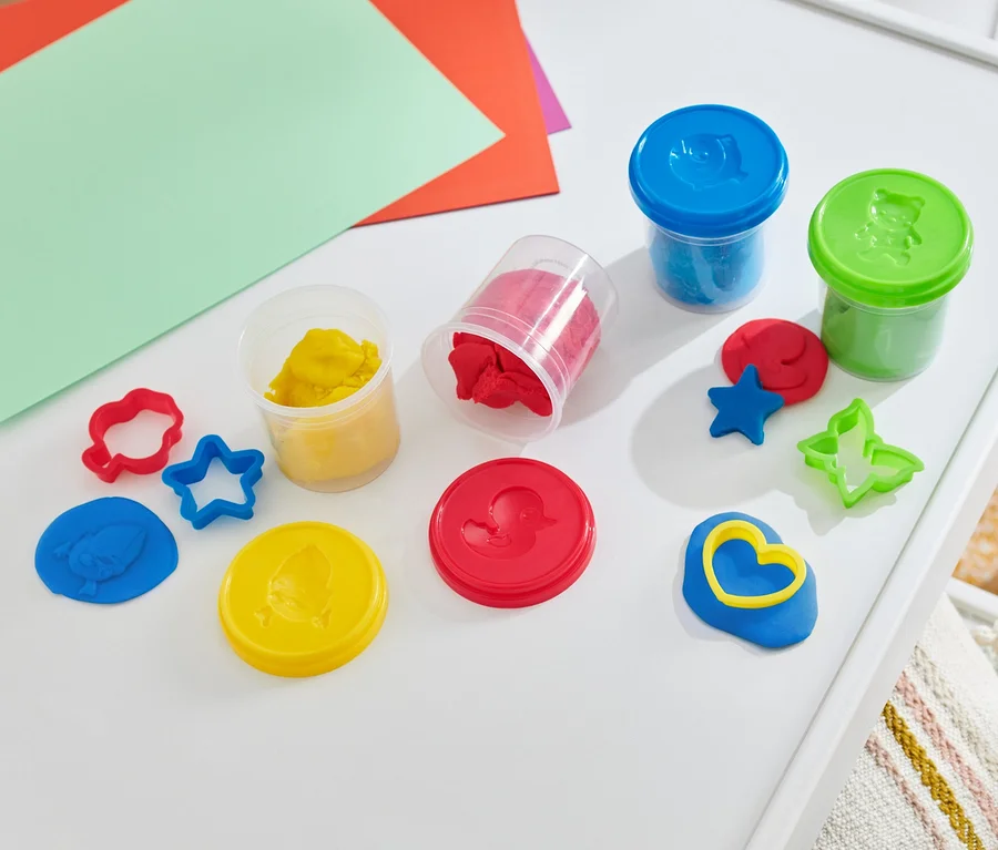 Kit de pâte à modeler sur une table blanche avec des papiers colorés.