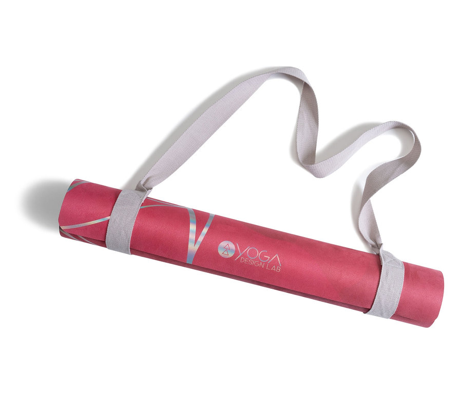 Un tapis de yoga rose enroulé avec le logo Yoga Design Lab et une sangle grise.